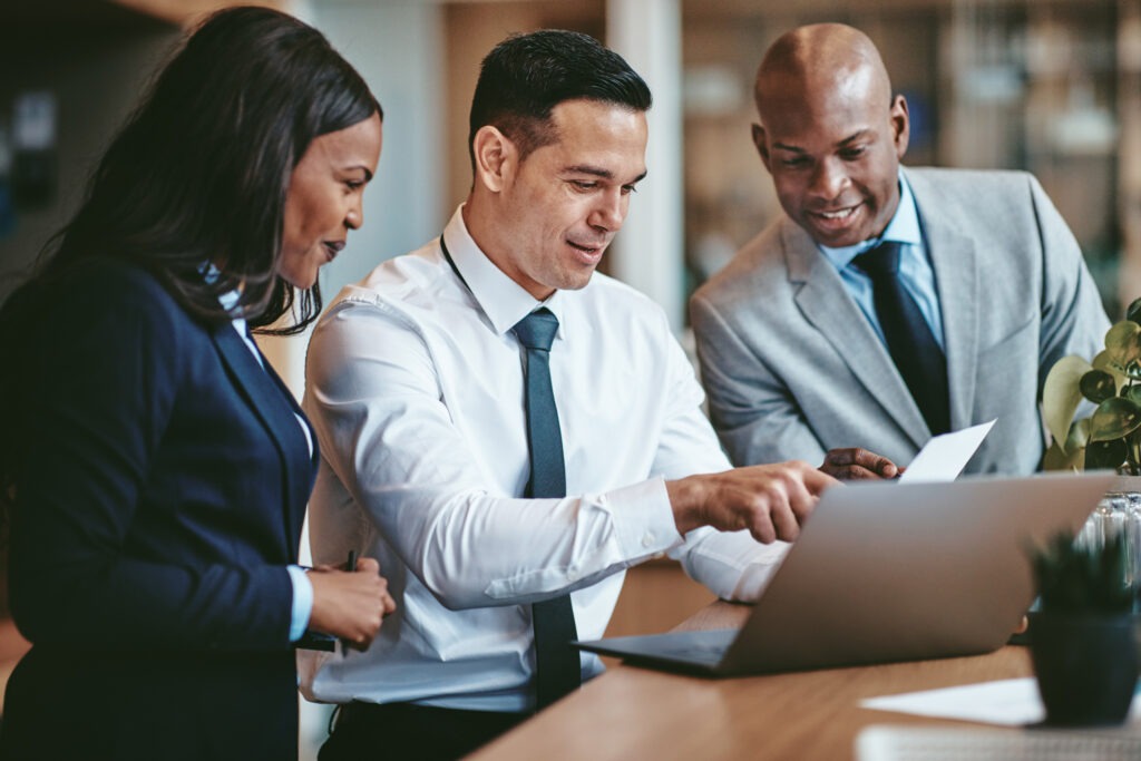 Diverse group of smiling businesspeople reading paperwork together while working.